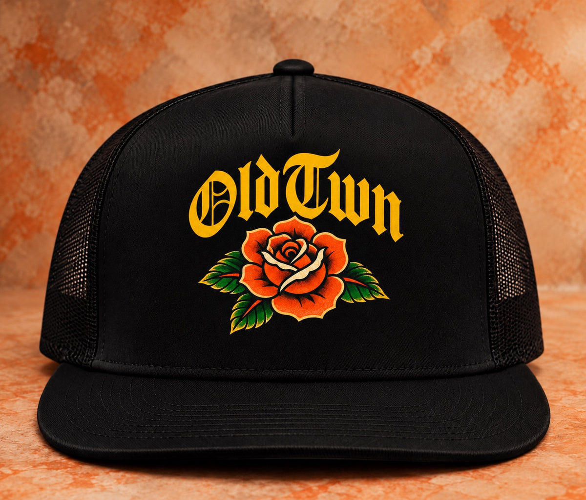 Black OLDTWN flat-bill mesh snapback with gold OldTwn lettering and rose full-color graphic print, front view